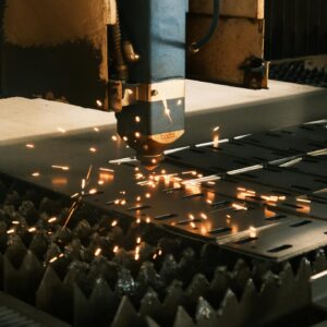 Close-up of a laser cutter in action, producing sparks in a modern manufacturing facility.